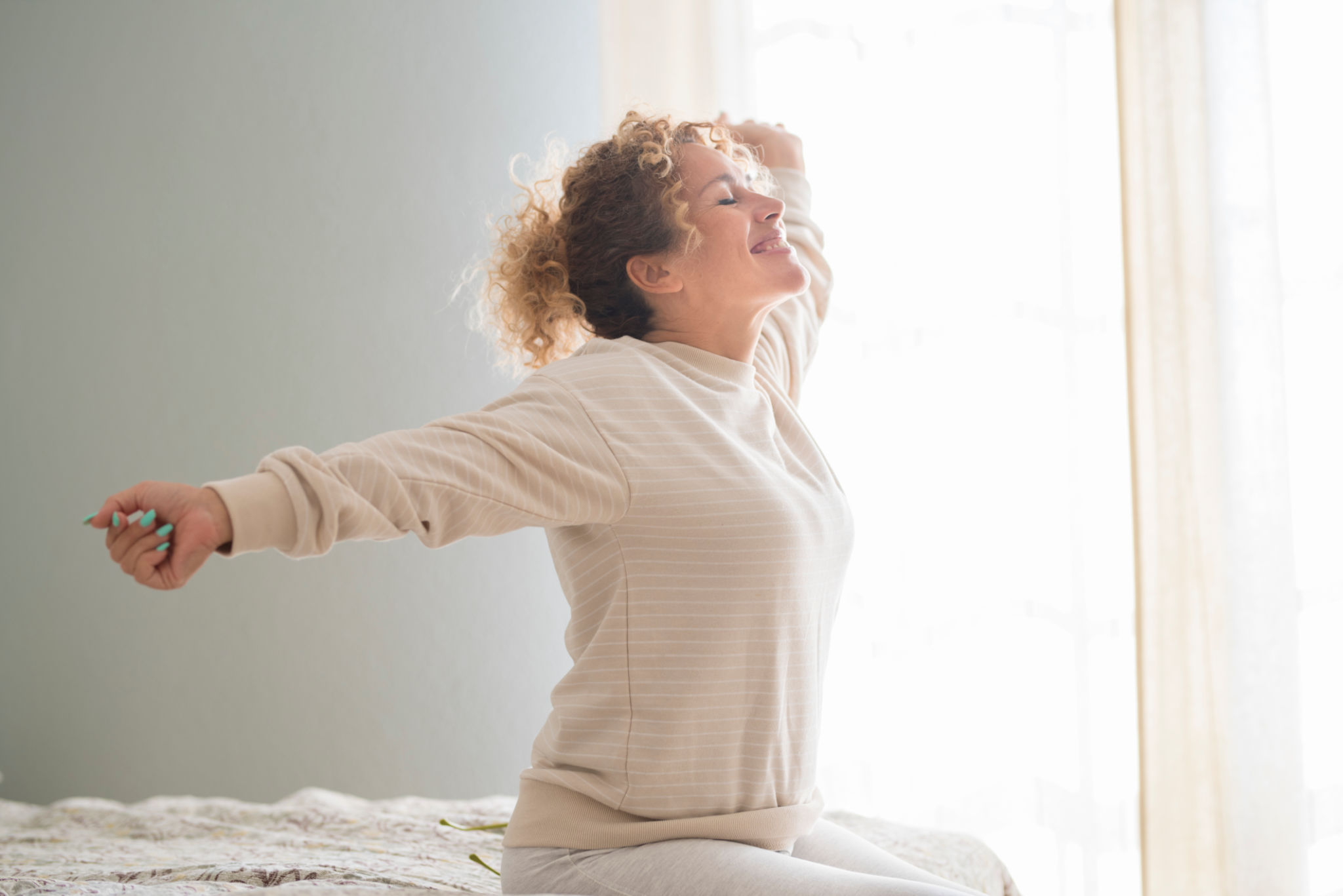 donna over 40 che si allunga al mattino con luce naturale, simbolo di equilibrio linfatico e leggerezza quotidiana