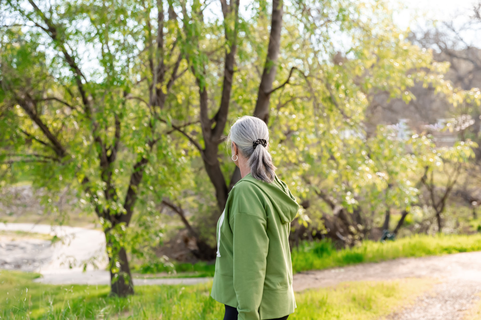 donna over 40 cammina lentamente all’aperto nel verde stimolando la circolazione linfatica e il benessere