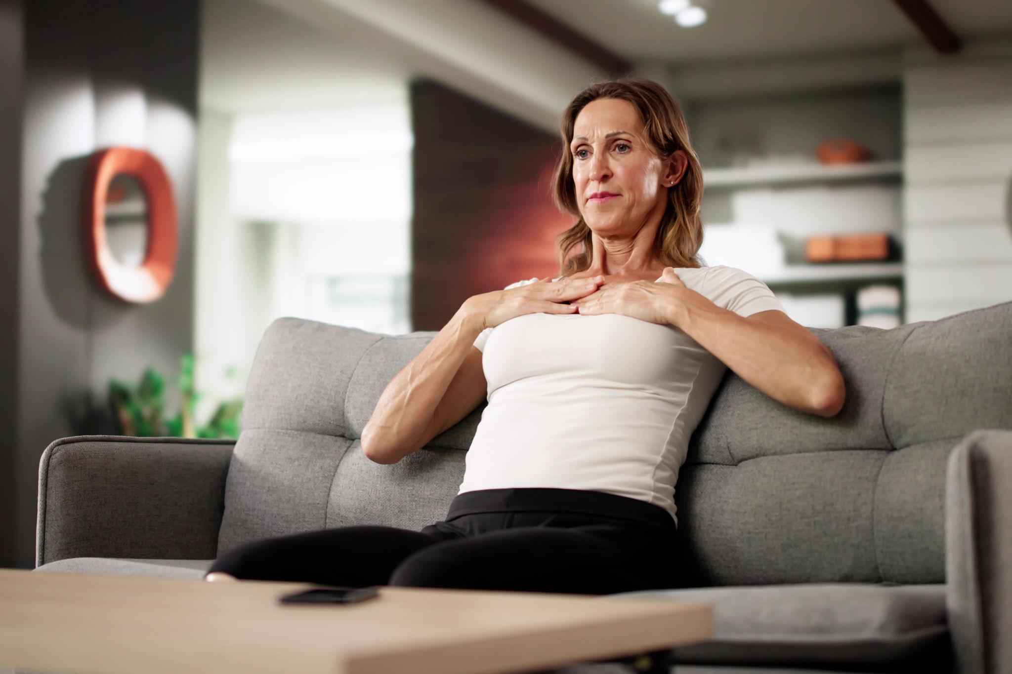 donna over 40 che pratica respirazione diaframmatica la sera sul divano per ridurre il gonfiore e dormire meglio