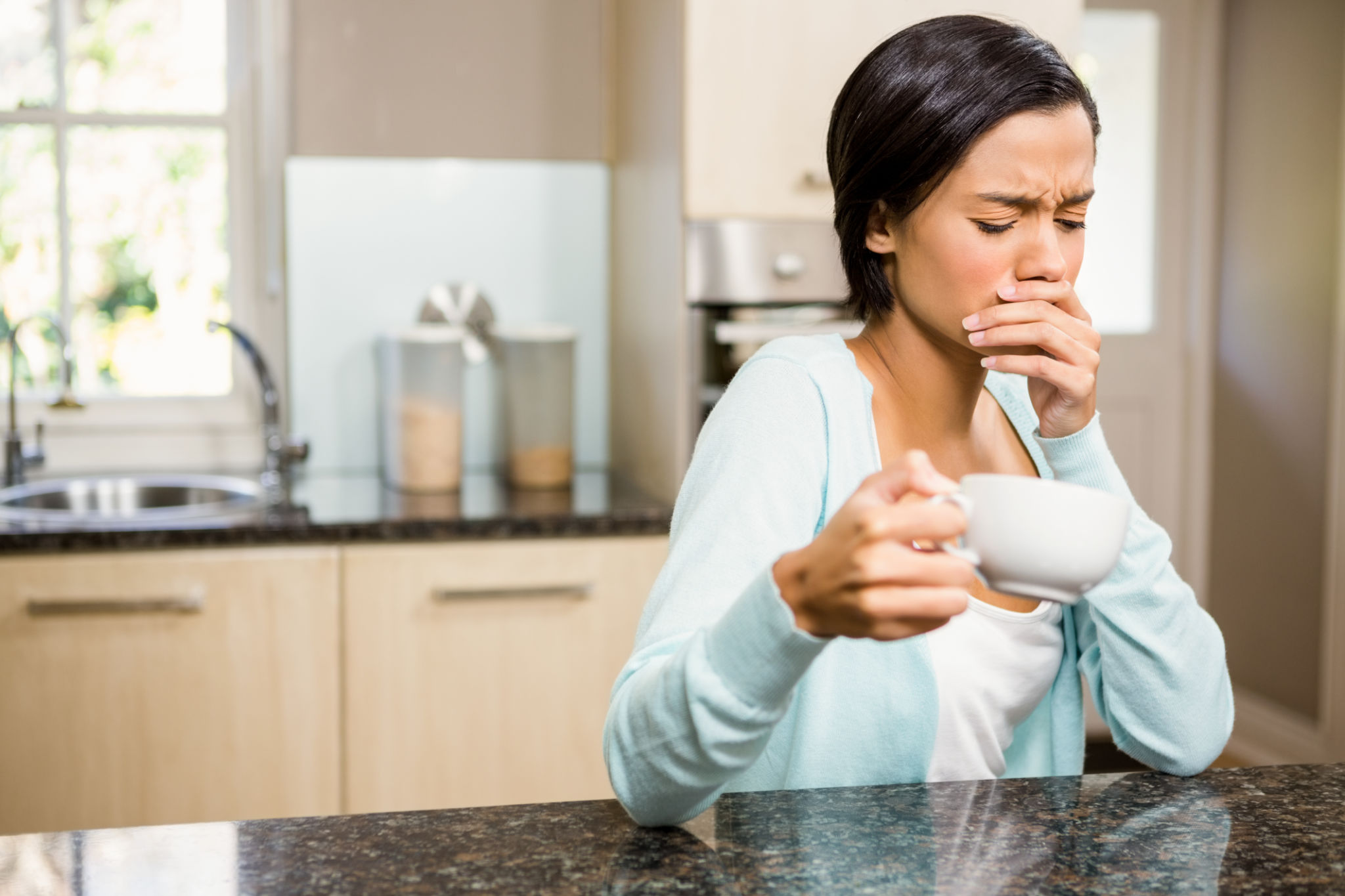 donna con nausea e fastidio allo stomaco dopo aver bevuto caffè al mattino