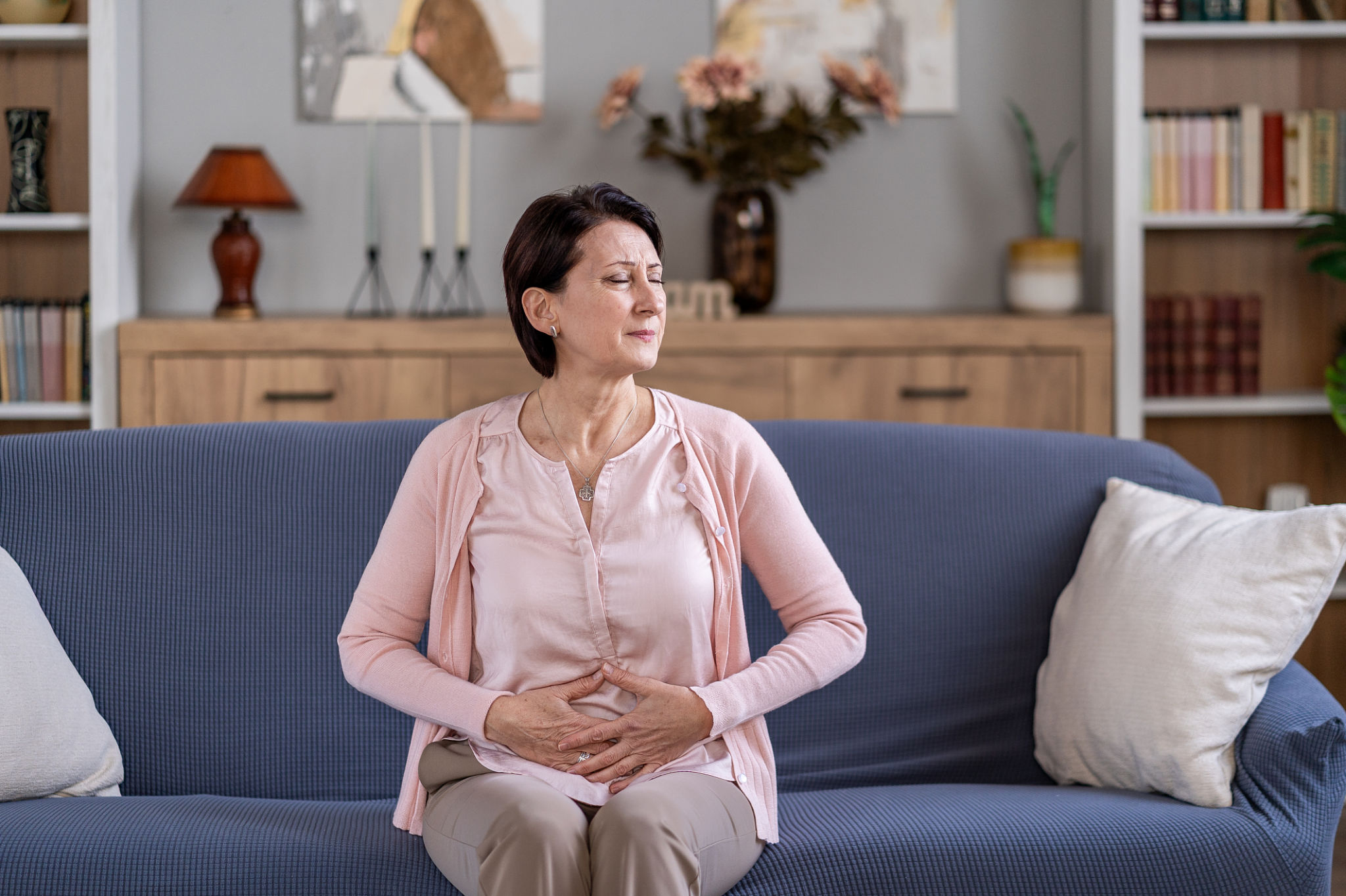 gonfiore in menopausa rimedi naturali donna con mano sull addome sul divano