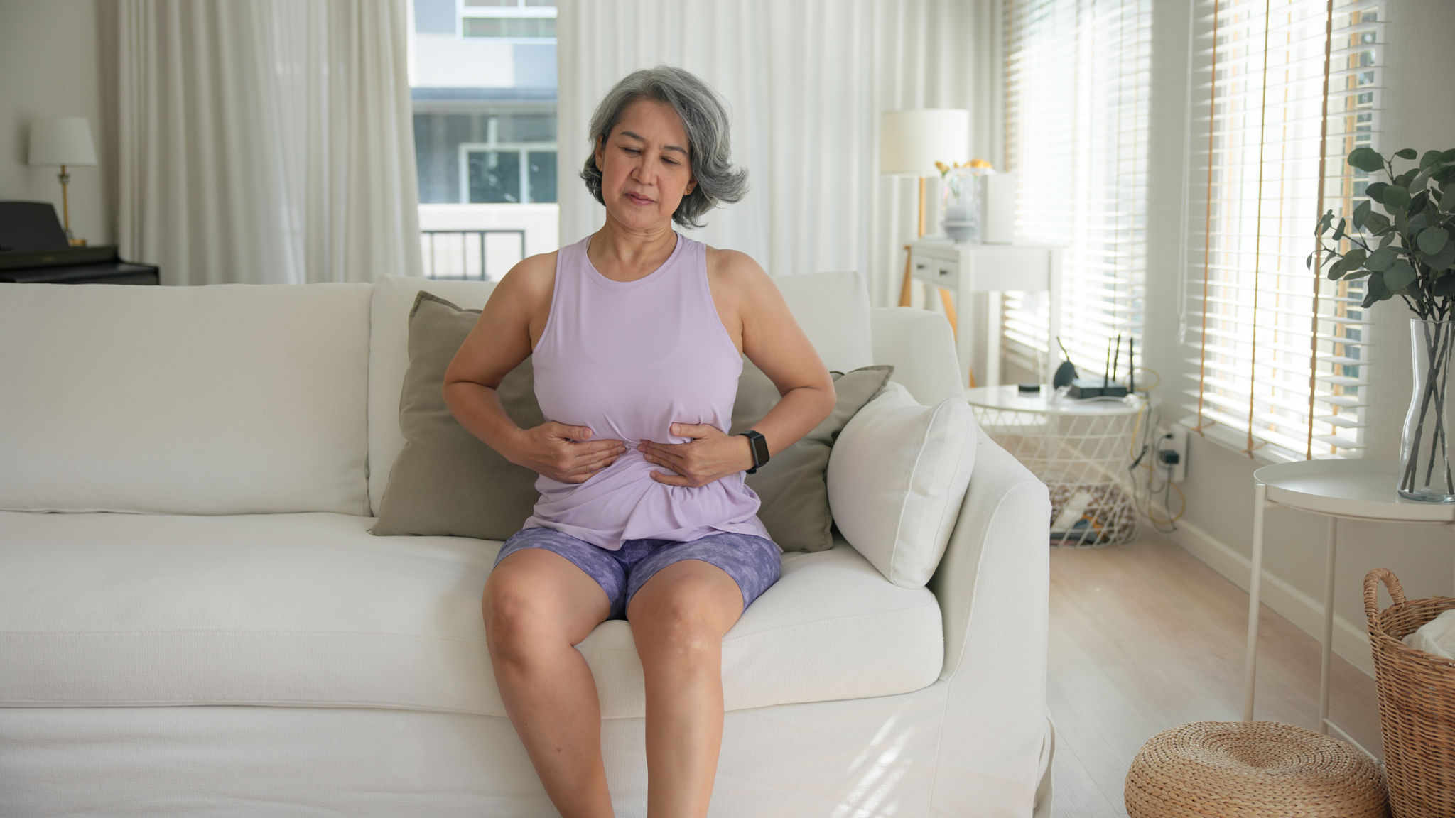 menopausa pancia gonfia dolorante fastidio addominale donna seduta sul divano