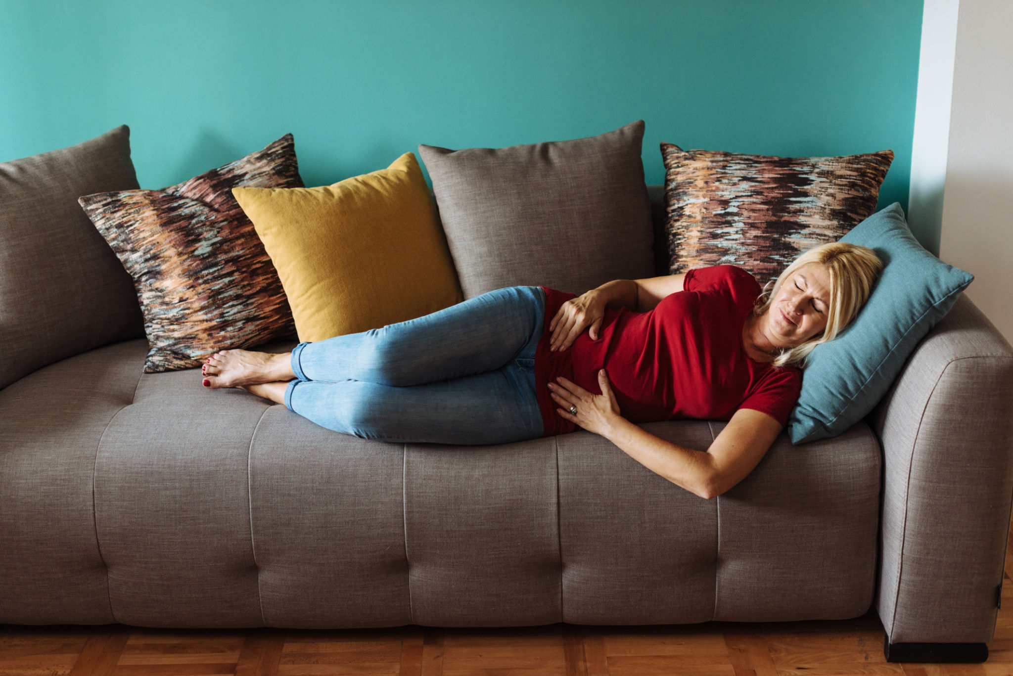pancia gonfia in menopausa anche se mangi bene con donna stanca sul divano in casa