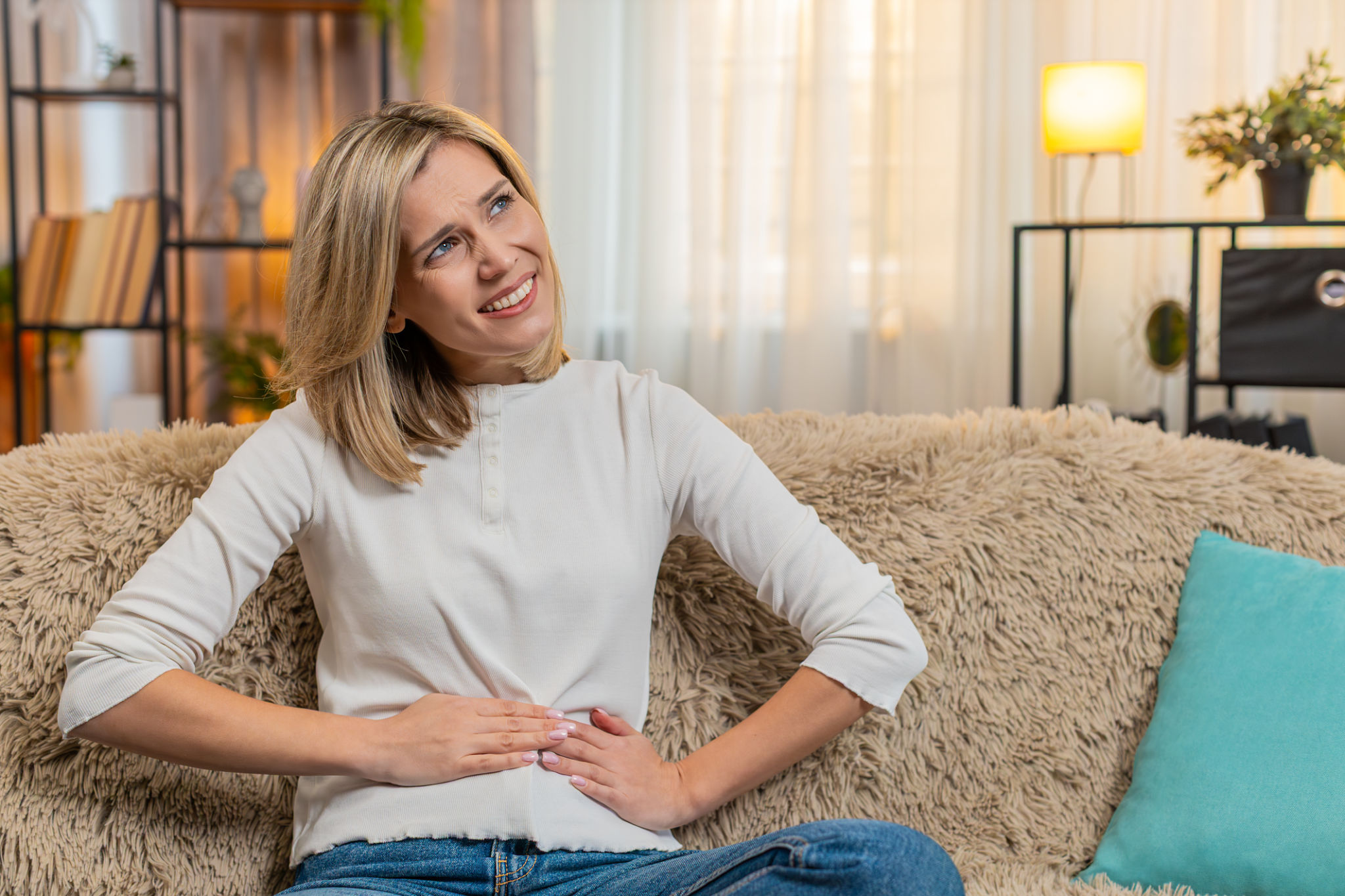 pancia gonfia in menopausa cosa fare donna seduta con mani sull addome in casa