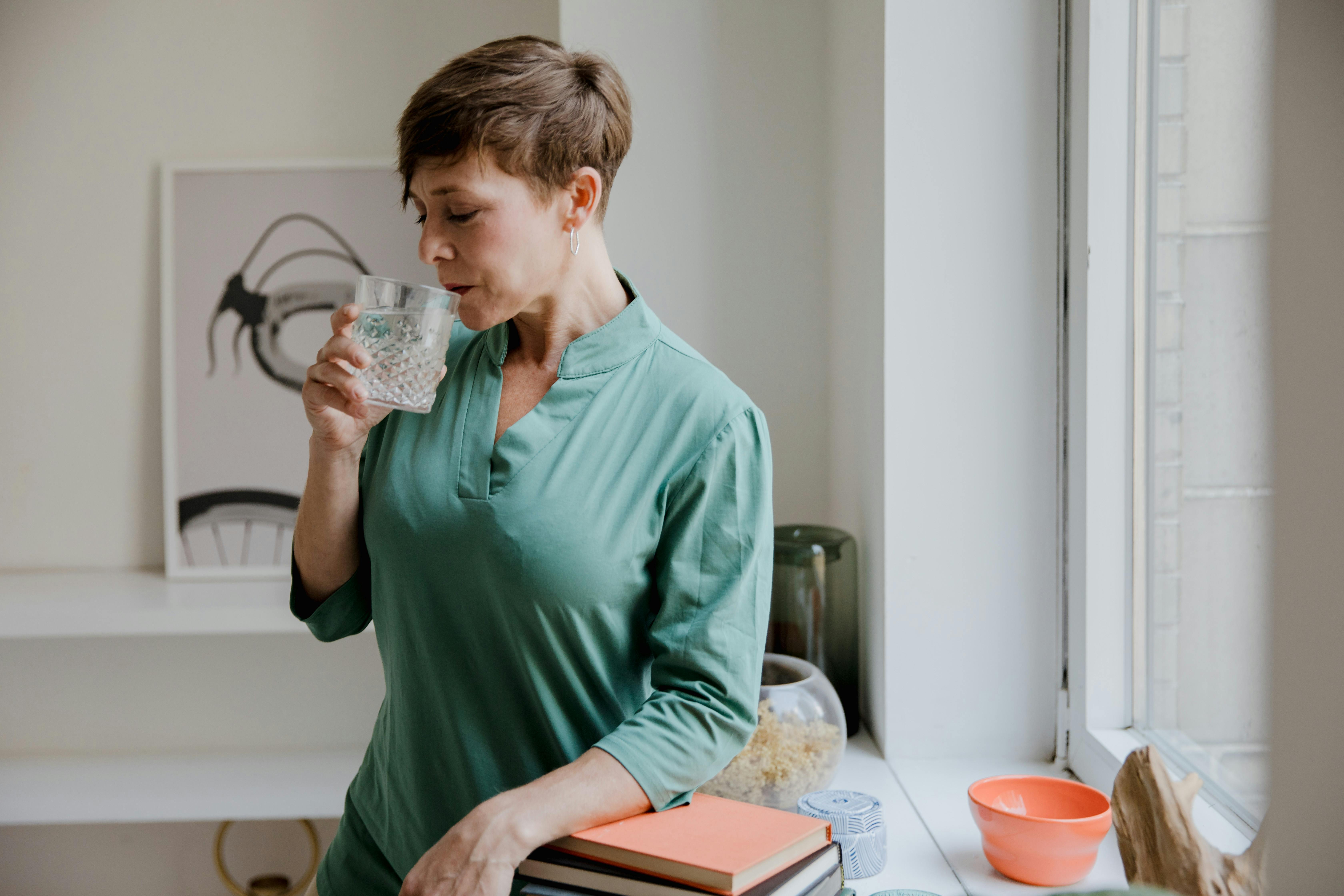bere poca acqua e gonfiore addominale donna che beve acqua in casa